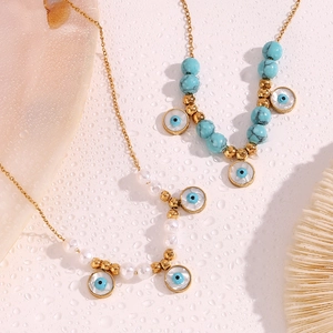 Detail of 18K gold-plated necklaces with blue turquoise beads and evil eye charms