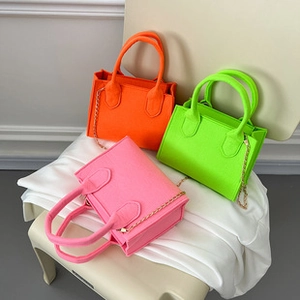 Three neon colored crossbody bags in pink, orange and green with golden chain straps