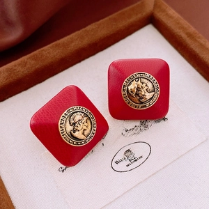 Macro view of red faux leather square earrings with a gold Alexander the Great coin inlay
