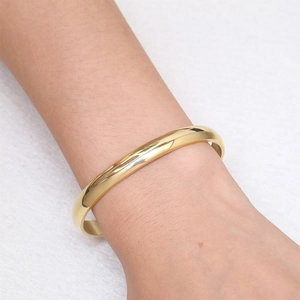 Close-up of minimalist gold titanium steel C-shape open bangle on a model's wrist