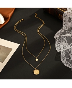 Detail showing 14K gold double-layer necklace with sunburst and star pendants on dark silk