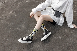 Detailed view of mid-calf socks with yellow, green, black and gray checkered patterns