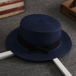 Detail of navy blue straw sun hat featuring exquisite woven texture and a black ribbon bow