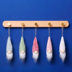 Set of five handmade gnome plush ornaments hanging on a wooden rack against blue background