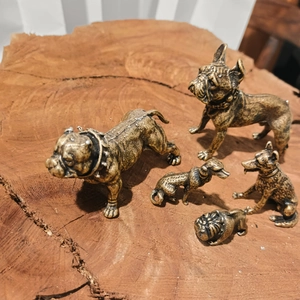 Set of five vintage bronze dog figurines displayed on a natural wood surface