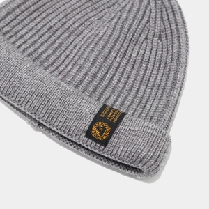 Gros plan sur le bonnet en maille côtelée grise avec l'écusson logo tissé GIGGER