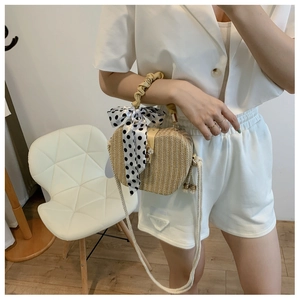 Detail of beige heart-shaped straw bag with ruched handle and polka dot silk scarf decoration