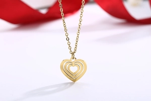 Macro shot of layered gold heart-shaped pendants with elegant red silk ribbon background