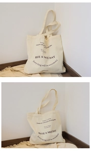 Detailed view of beige canvas tote bag with black lettering on a cozy blanket background
