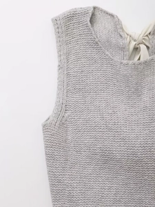 Vue détaillée du gilet en maille grise avec un nœud en ruban blanc au dos