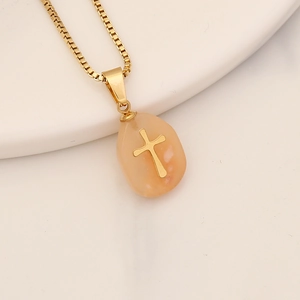 Macro shot of light orange natural stone pendant with gold cross and stainless box chain