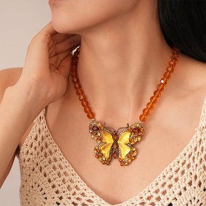 Macro detail of amber butterfly pendant with sparkling rhinestones and beaded chain