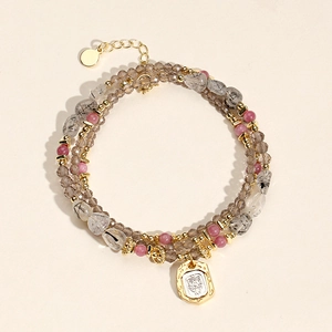 Detail of layered beaded bracelet with grey faceted stones, black rutilated quartz and gold charms