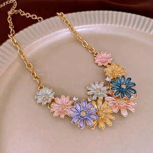 Detailed macro of colorful daisy enamel flower necklace with gold chain and crystals