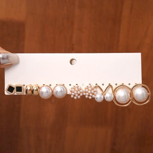 Detail of 12-pair pearl stud earring set with gold floral designs and black enamel accents