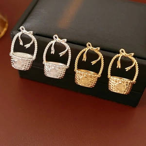 Close-up of golden and silver flower basket earrings with bow detail on a jewelry box