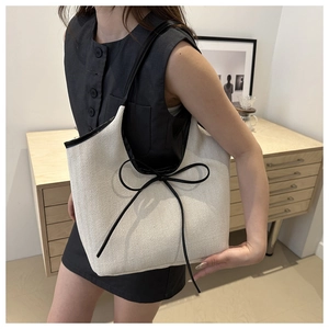 Detail of the woven canvas tote bag with large black bow decoration and contrasting trim