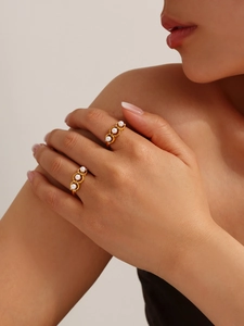 Close-up of adjustable gold pearl ring featuring hollow-out bands and zircon accents