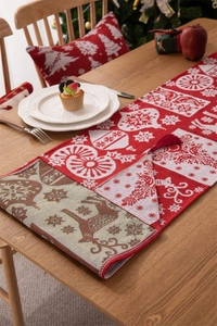 Dettaglio del runner da tavola natalizio rosso e bianco con nappe e motivi a renna festivi