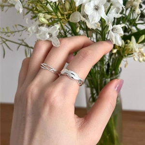 Elegant 925 sterling silver intertwined and twisted rope rings on a hand with flowers