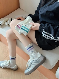 Detail of white striped athletic mid-calf socks with Smile embroidery and ribbed cuffs