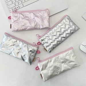Gros plan de trousses matelassées avec motifs de cœurs et nœuds en rose et argent métallisé