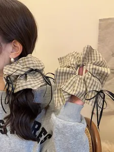 Detail of plaid scrunchies with black ribbons shown on hair and in hand