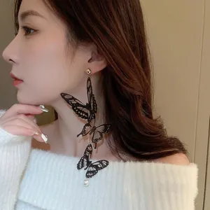 Boucles d'oreilles longues papillon en acrylique avec pompons perles sur mannequin