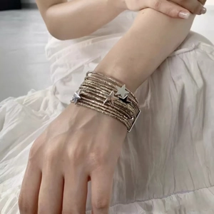 Multi-layer champagne gold wrap bracelet with star charms on model against white fabric