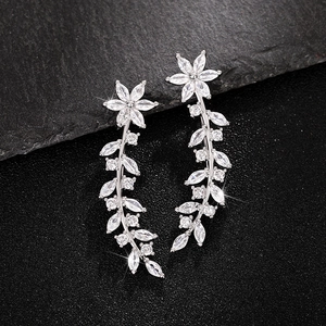 Sparkling silver floral earrings with zircon vine leaves on a dark stone background