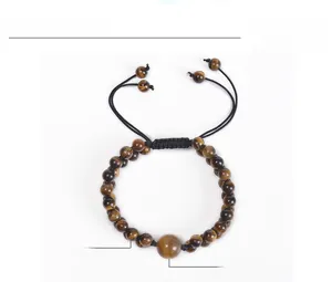 Macro shot of 6mm and 12mm tiger eye stone beads on a black woven adjustable bracelet