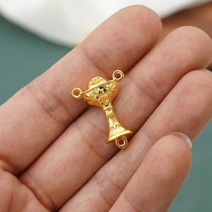 Macro view of gold IHS holy grail rosary connector held in hand for jewelry making