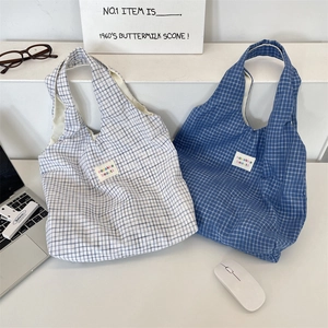 Détail des sacs fourre-tout à carreaux bleus et blancs avec étiquettes de marque tissées