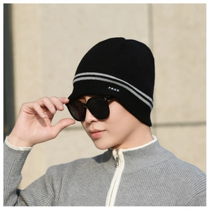 Close-up of black knitted beanie with grey stripes and stitched label detail