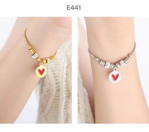 Detail of gold and silver snake chain bracelets featuring red heart charms and crystal beads