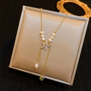 Detail of baroque pearl necklace with golden Y-shaped tassel and marquise floral pendant