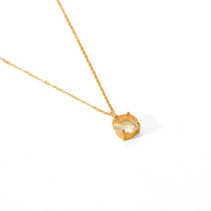 Detail of four-prong gold-plated necklace with a faceted yellow round-cut gemstone
