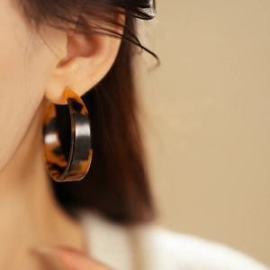 Close-up of tortoise shell resin C-shaped hoop earring on a female model