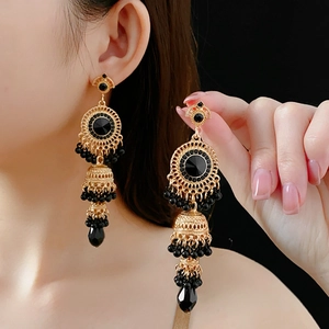 Close-up of vintage gold layered drop earrings with black crystals on a female model