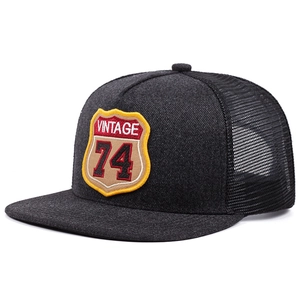 Macro detail of dark grey trucker hat with Vintage 74 embroidery and mesh back