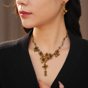 Detail of vintage flower jewelry set featuring orange and green rhinestones on model