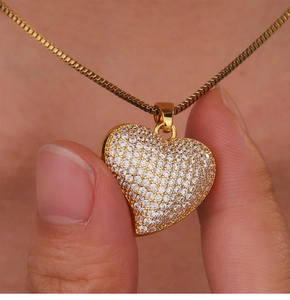 Detailed close-up of a gold heart pendant with pavé cubic zirconia on a cable chain