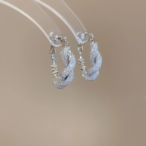 Detailed view of silver hoop earrings featuring a sparkling mesh design and twisted rope texture