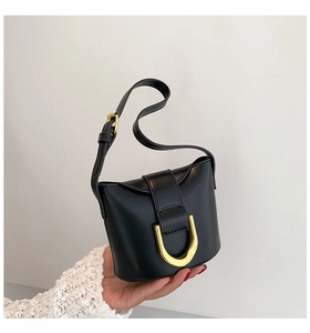 Close-up of black leather handbag featuring a unique gold U-shaped metal buckle lock