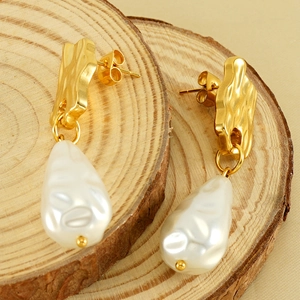 Boucles d'oreilles dorées irrégulières avec perles baroques sur fond en bois rustique