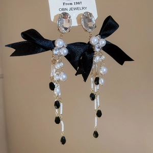 Close-up of elegant bow drop earrings with pearls and crystals in vintage tassel style