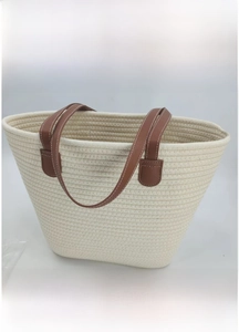 Detailed close-up of a cream woven cotton tote bag with brown leather handles and spacious interior