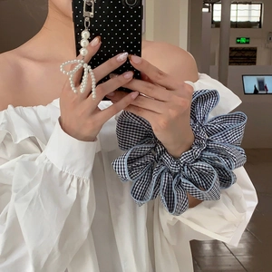 Oversized blue and black checkered mesh scrunchie hair tie worn on a female wrist
