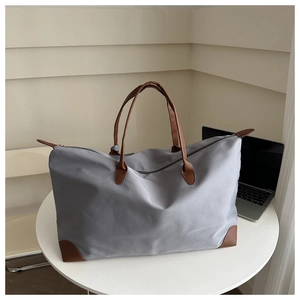 Detail of grey Oxford tote with brown leather handles on a white minimalist table