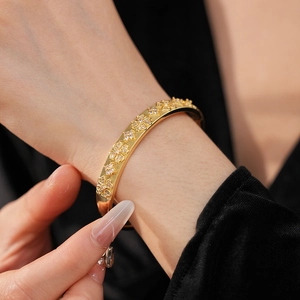 Close-up of gold plated flower bangle with sparkling zircon stones on female wrist